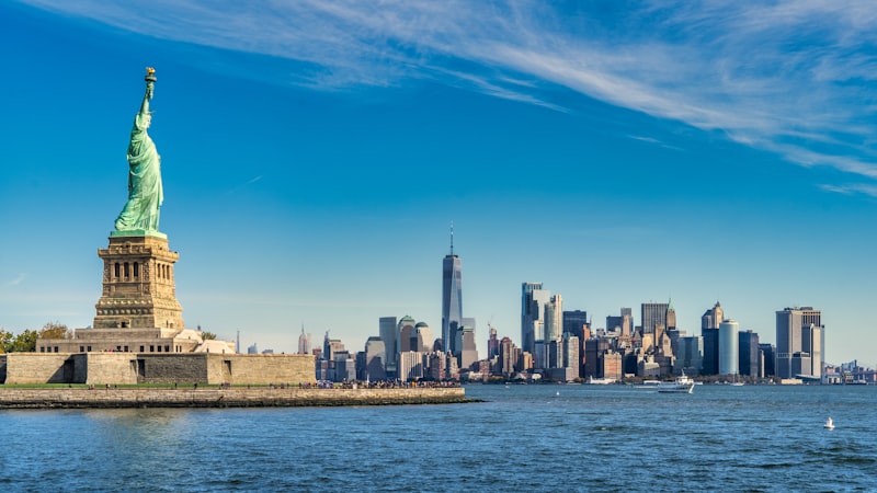 Statue of Liberty standing tall against a blue sky above New York Harbor
